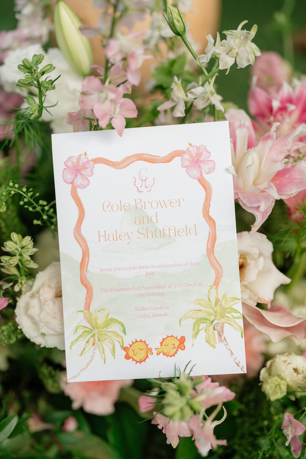 Hand-painted watercolor wedding invitation for Cole and Haley at Paliku Gardens in Oahu, Hawaii, with pink hibiscus, palm trees and two smiling pufferfish