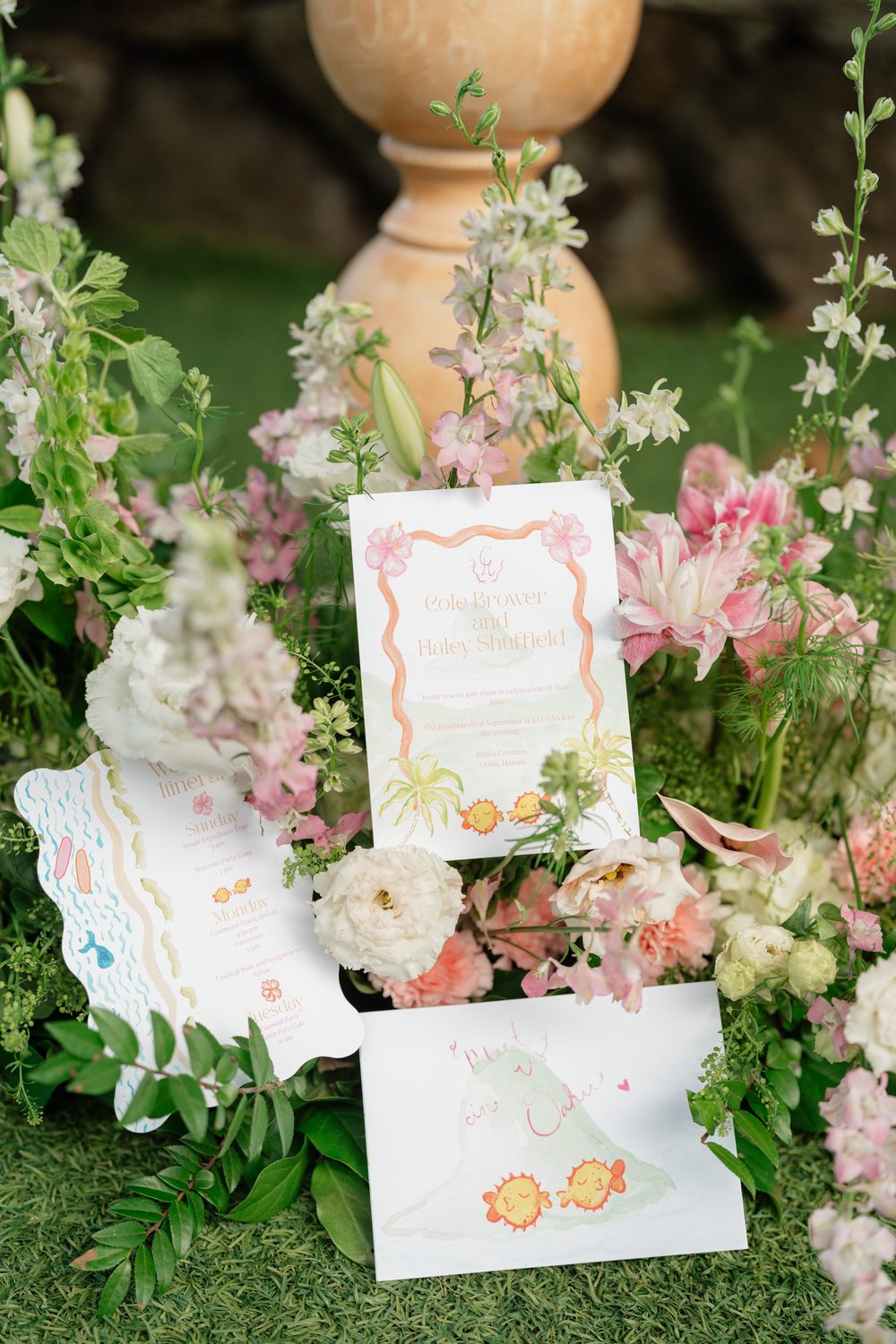 The Oahu wedding suite styled in flowers: the invitation, a scallop-edged weekend itinerary card and a hand-lettered envelope liner