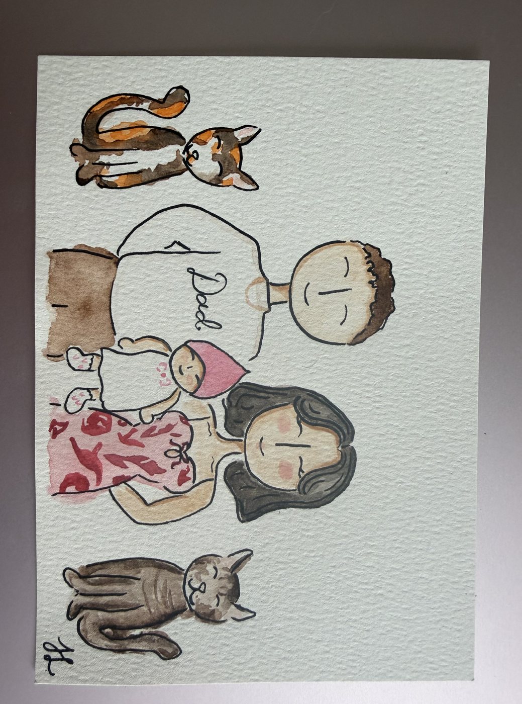Watercolor family portrait of a dad in a lettered shirt, a mom, a young girl and a baby, with the family&rsquo;s two cats stretched out above and below them