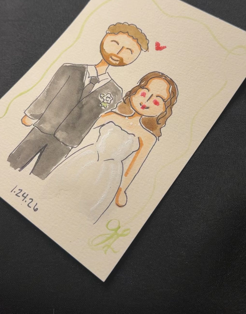 Live wedding guest portrait of a couple, the groom in a grey suit and the bride in a white gown with a red heart beside them, dated 1.24.26