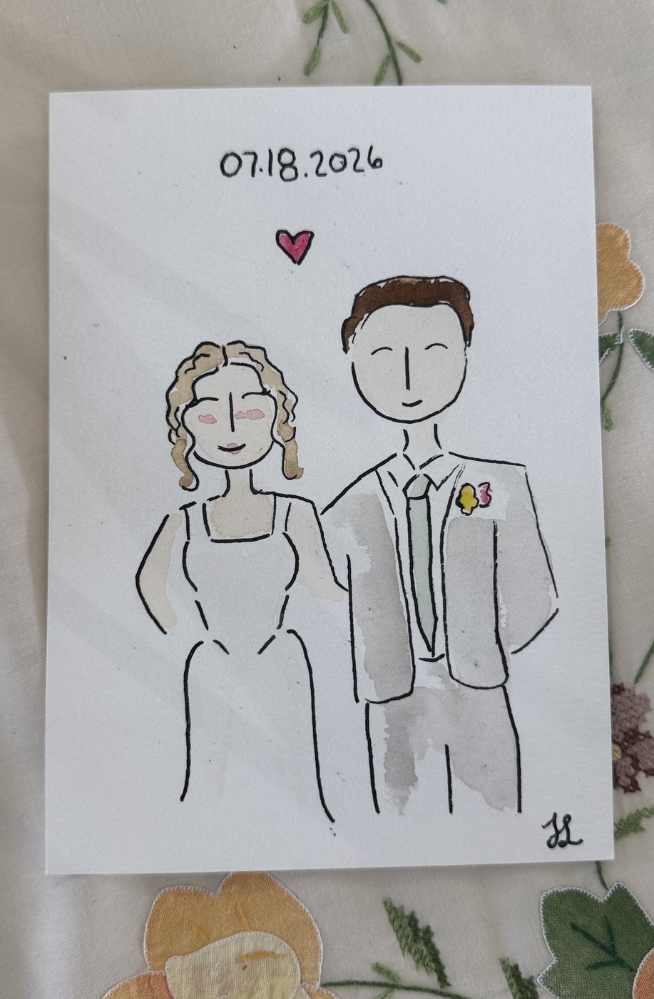 Live guest portrait of a bride in a white gown beside a groom in a light suit, dated 07.18.2026